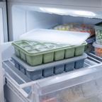 Two lidded LeakGuard ice cube trays stacked flat inside a clean freezer drawer